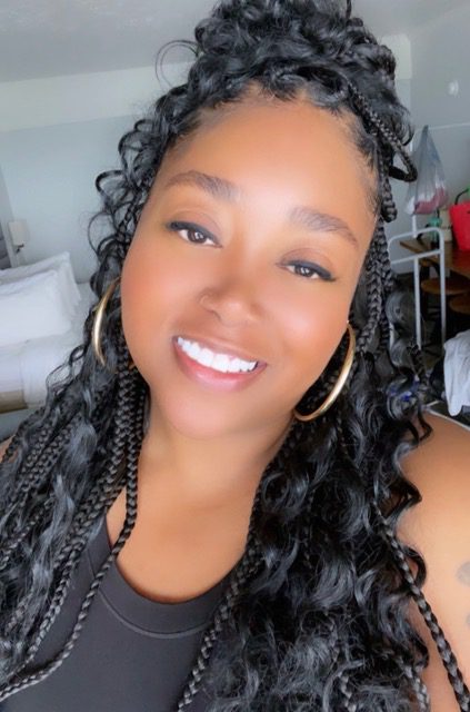 A smiling woman with curly hair and hoop earrings.