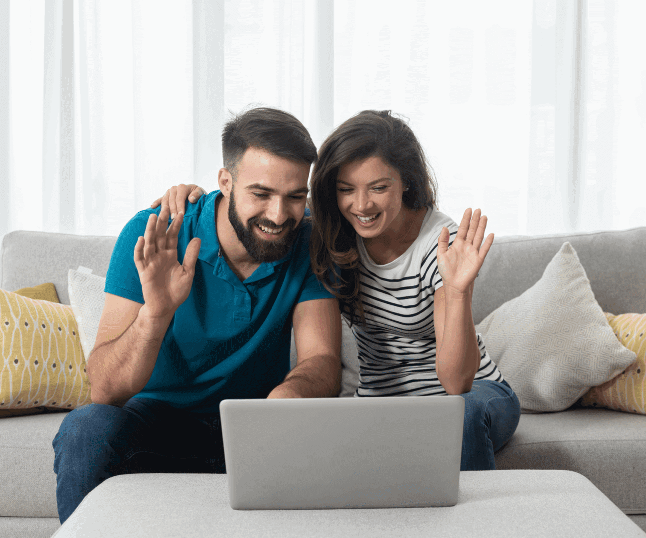 Couple happily video chatting on laptop at home.