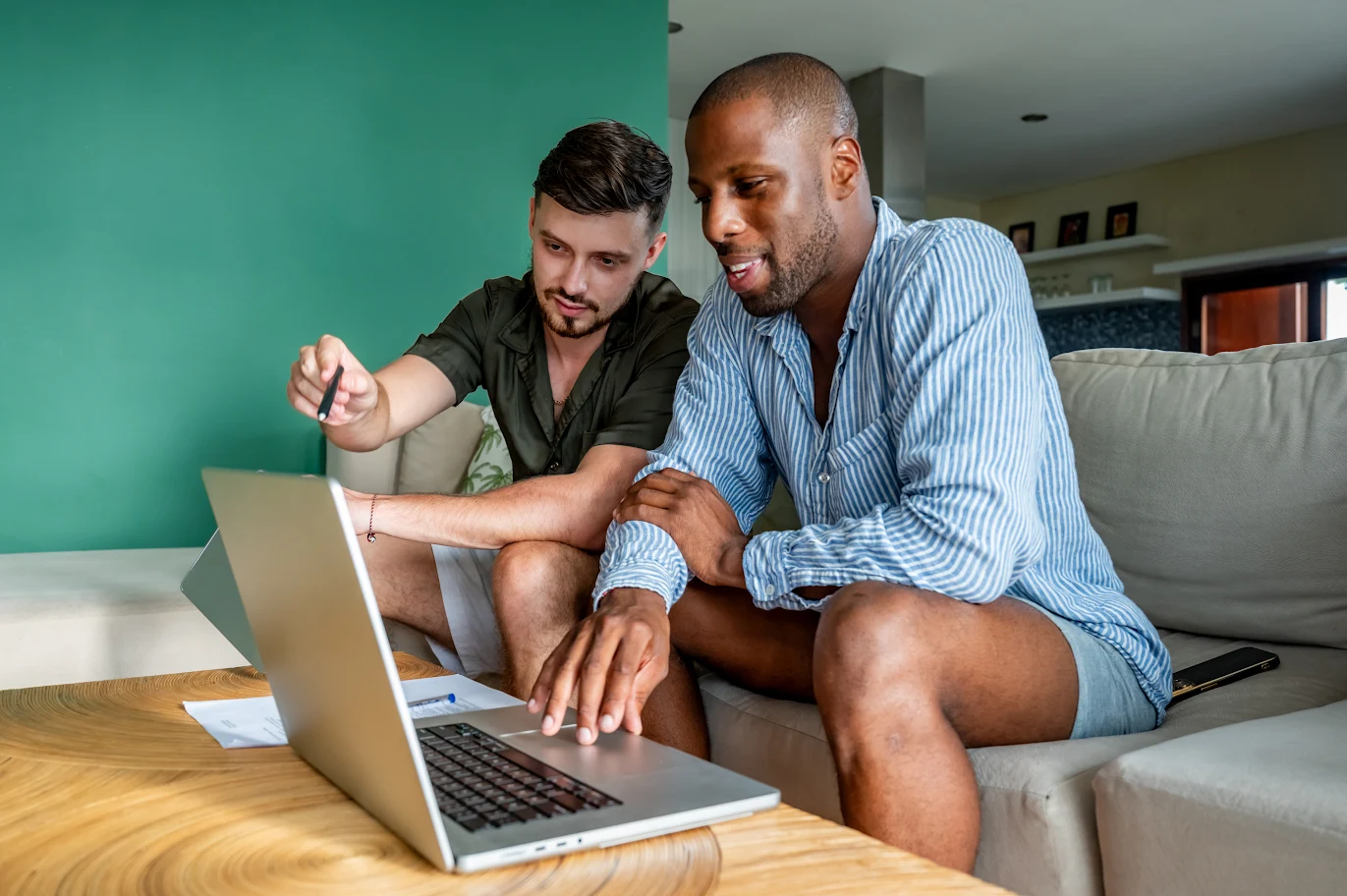 Two men collaborating on a laptop at home.