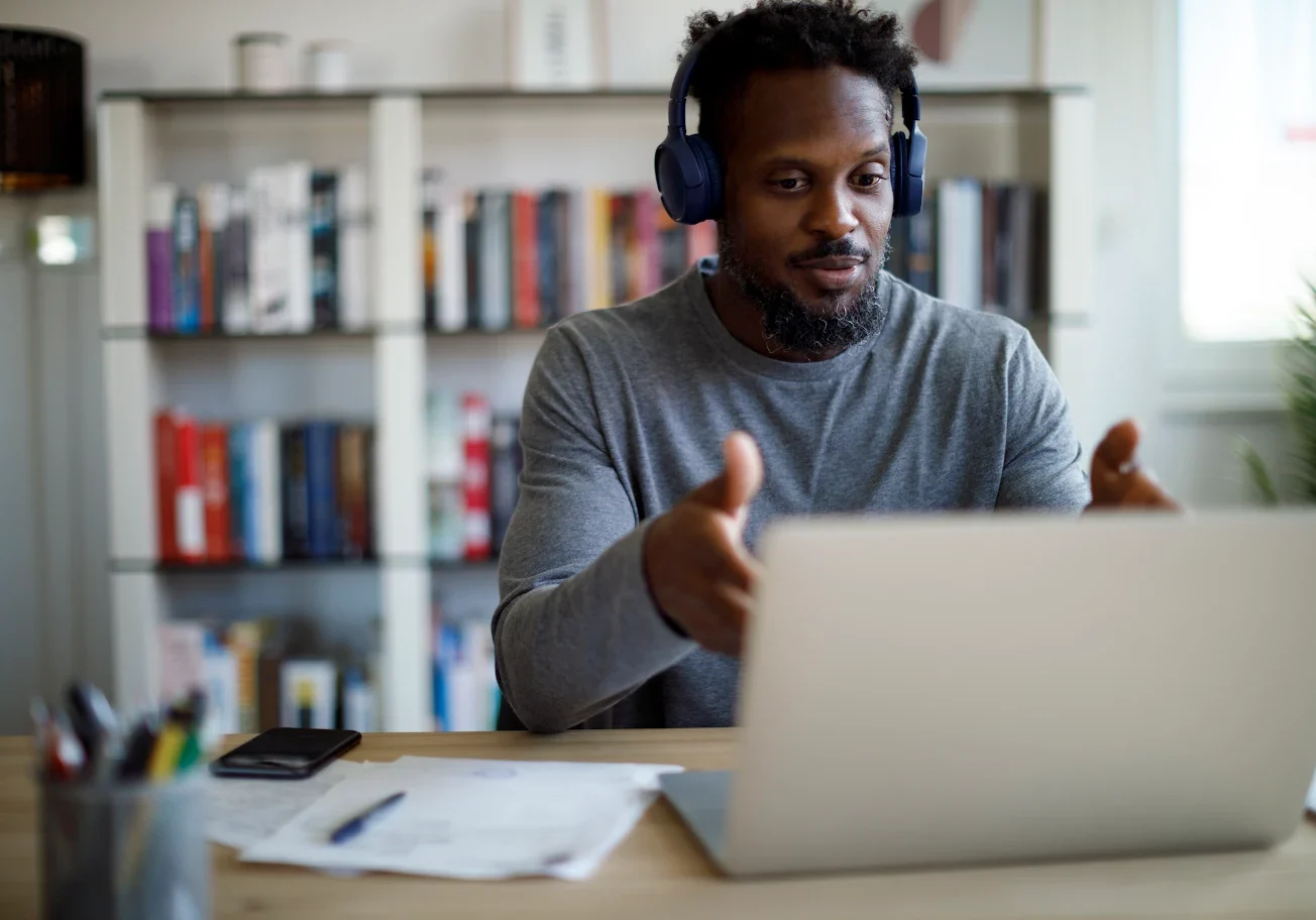 Man wearing headphones working on a laptop at home.